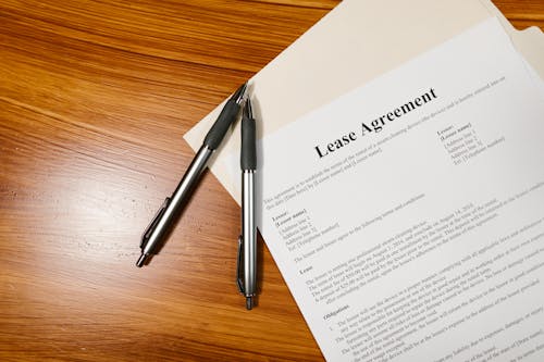 How to Legally Handle a Tenant’s Breach of Lease Agreement Free High-angle view of a lease agreement and pens on a wooden desk. Stock Photo